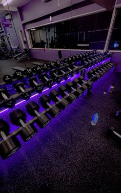 an empty gym with rows of black chairs and purple lighting on the floor in front of it