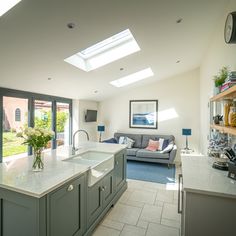 an open kitchen and living room area with skylights above the counter top, in a modern style home