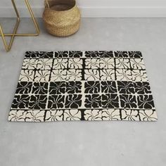 a black and white area rug on the floor next to a basket with a plant in it