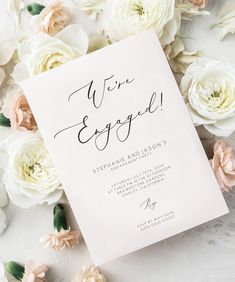 a wedding card with the words we're engaged on it surrounded by white and pink flowers