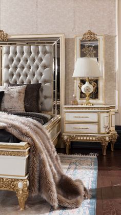 a bedroom with gold and white furniture and fur on the bed, nightstands and mirror