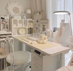 a white desk topped with lots of drawers next to a lamp and window sill