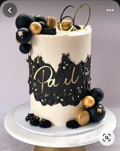 a white and black cake with gold decorations on it's top, sitting on a table