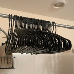 there is a rack with many black clothes hanging from it's hooks on the wall