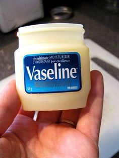 a hand holding a small jar of vaseline