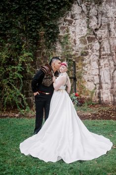 a bride and groom kissing in front of a stone wall