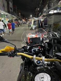 a motorcycle parked on the side of a street next to people walking down the street