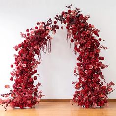 an arch made out of red flowers on a wooden floor