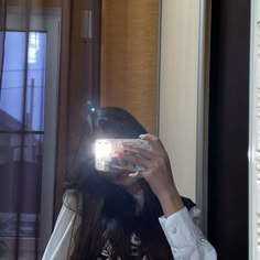 a woman taking a selfie in front of a mirror with her cell phone up to her face