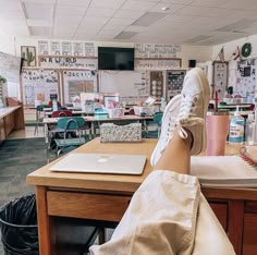 a person's feet resting on a desk in a classroom