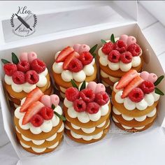 a box filled with lots of cupcakes covered in frosting and topped with raspberries