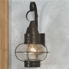 a light that is on the wall next to a wooden pole and some concrete walls