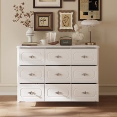 there is a white dresser with many pictures on the wall above it and other decorations