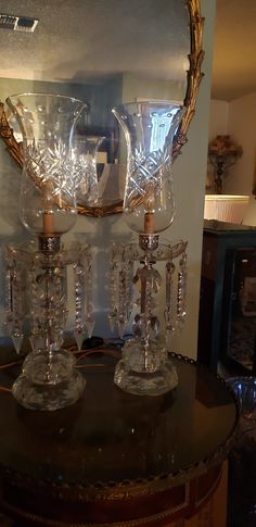 three crystal goblets sitting on top of a wooden table next to a mirror