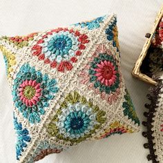 two decorative crocheted pillows sitting on top of a white bed next to each other