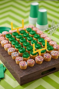 cupcakes with green frosting and sprinkles on a wooden board