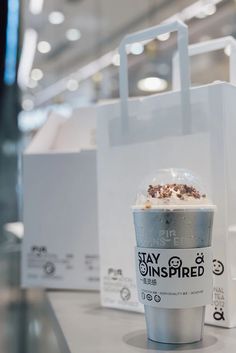 a cup of coffee sitting on top of a counter next to a white paper bag