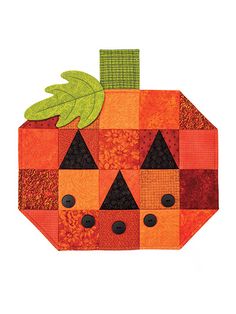 an orange patchwork pumpkin with black eyes and green leaves on it's head