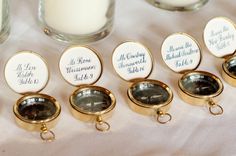 an image of some gold and white tags on a table with candles in the background