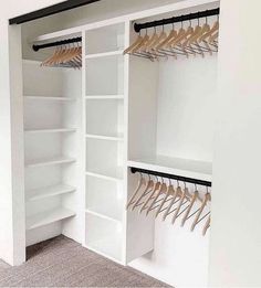 an empty closet with white shelves and wooden hangers