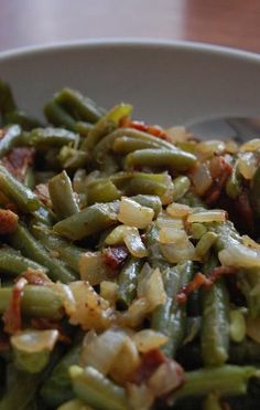 a white bowl filled with green beans and bacon