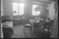 an old black and white photo of a living room with couches, tables and chairs