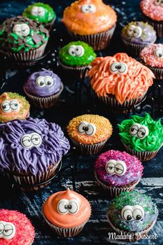 colorful cupcakes with eyes and googly eyes are on a black tablecloth