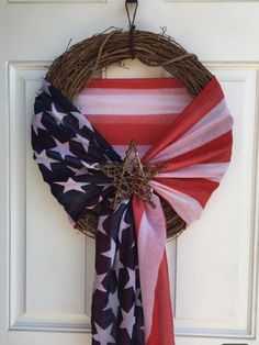 a patriotic wreath hanging on the front door with red, white and blue scarves