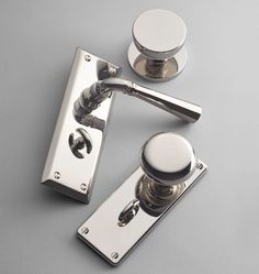 two chrome door handles and knobs on a gray surface