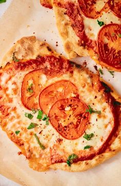 two slices of pizza with tomatoes on them sitting on top of a white paper towel