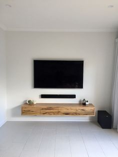 a flat screen tv mounted to the side of a wall in a white living room