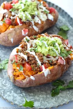 two loaded sweet potatoes on a plate with guacamole