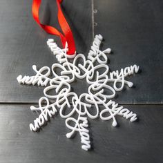 a white snowflake ornament with a red ribbon hanging from it's side