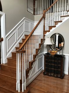 there is a mirror on the table in front of the stair case and an end table