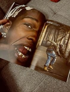 an open book showing a man's mouth and teeth with his hands on the pages