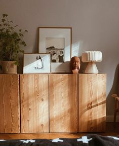 a wooden cabinet sitting next to a lamp on top of a hard wood floor covered in black and white rug