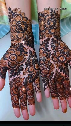 two hands with henna designs on them, one is brown and the other is black