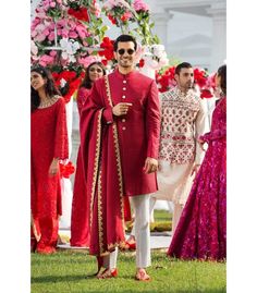 a man in a red outfit standing next to other people wearing pink and white outfits