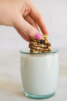 a hand picking up a cookie from a glass bowl