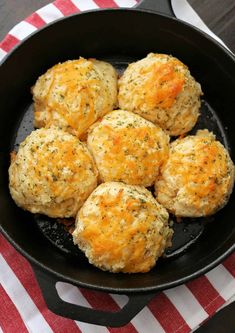 some biscuits are in a black pan on a red and white tablecloth with a striped napkin