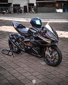 a black motorcycle with a helmet on it's seat is parked in front of a building