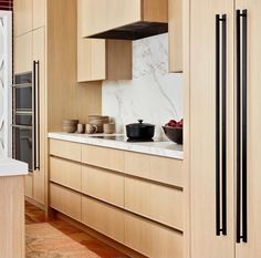 a kitchen with wooden cabinets and white marble counter tops, along with an oven hood