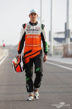 a man in an orange and black outfit is walking down the street with his helmet on