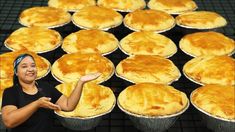 a woman is pointing to some pies on a rack