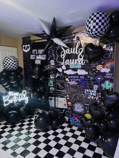 a room filled with black and white balloons next to a checkerboard wall covered in writing