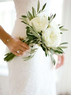 a bride holding a bouquet of white flowers