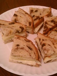 a white plate topped with cut in half sandwiches on top of a wooden table next to a cup