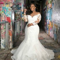 a woman in a white wedding dress standing next to graffiti covered walls with her hands on her hips