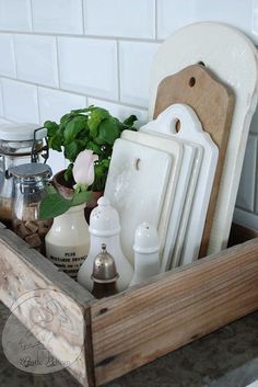 a wooden tray filled with white dishes and utensils on top of a counter