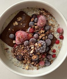 a bowl filled with oatmeal topped with fruit and nuts next to a chocolate bar